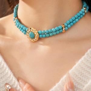 Détail du collier de perles turquoise double rang avec pendentif doré sur le mannequin