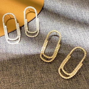 Pave crystal paperclip earrings in gold and silver finish on a textured background