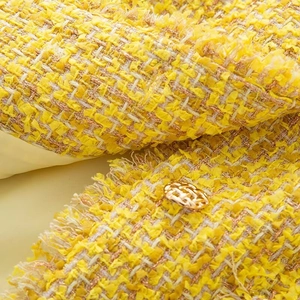 Close-up of yellow tweed fabric with gold metallic thread and hollow metal button