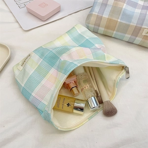 Detail showing two sizes of checkered cosmetic bags with makeup items inside