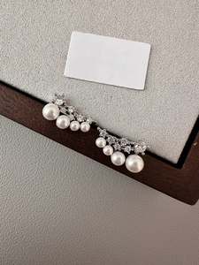 Detailed view of silver curved earrings with gradient pearls and sparkling cubic zirconia