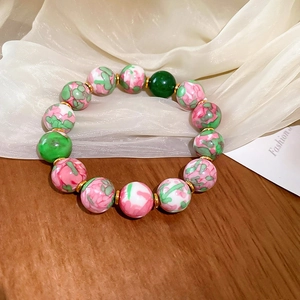 Detail of red and green gradient glass beads with golden metal spacers on a bracelet