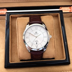 Detail view of quartz watch with white Roman dial and brown leather strap in a gift box