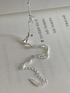 Macro shot of S925 silver bow bracelet on book page with wavy chain detail
