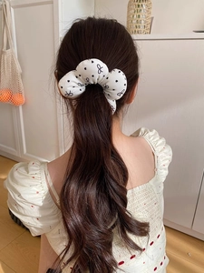 Rear view of a model wearing a large white floral scrunchie with black bow patterns