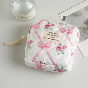 Detail view of quilted floral cosmetic bag with pink ribbon and rose patterns
