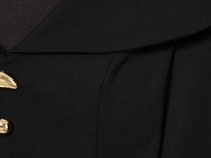 Macro shot of elegant black blazer collar featuring textured fabric and gold button detail