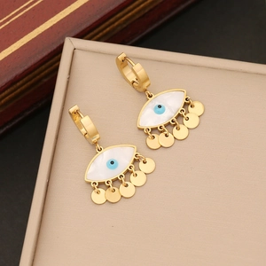 Golden evil eye earrings with mother of pearl and dangling coin charms on a tray
