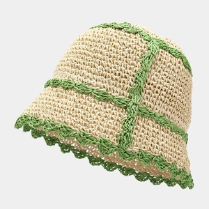 Close-up of handmade straw bucket hat with beige texture and green wavy crochet detail