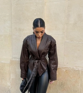 Détail de la veste en cuir marron foncé avec ceinture à la taille et design d'épaule unique