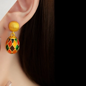 Close-up of vintage enamel drop earrings with colorful geometric patterns on model
