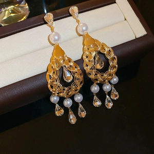 Detailed close-up of golden vintage drop earrings with pearls and crystals on a gift box