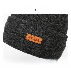 Detail of dark gray knit beanie texture with orange brown embossed leather brand patch
