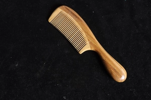Detailed texture of thick green sandalwood comb with rounded handle and fine teeth