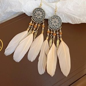 Detail of bohemian long feather tassel earrings with vintage bronze leaf and wood beads