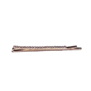 Detail shot of a sparkling rhinestone bobby pin with a rose gold finish on white backdrop