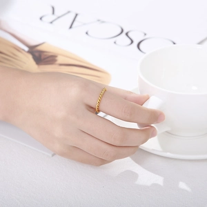 Minimalist twisted gold titanium steel ring shown on model finger with fashion magazine