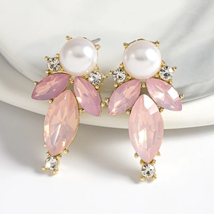 Close-up of teardrop earrings with pink crystals and pearls on a marble plate