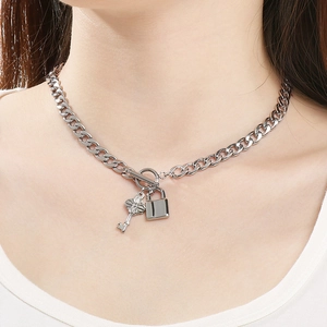 Gros plan détaillé d'un collier argenté avec pendentif clé et cadenas et chaîne à maillons