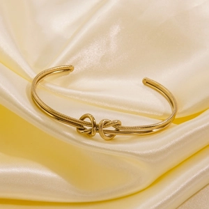 Detail of gold knot cuff bracelet featuring textured and polished dual metal strands