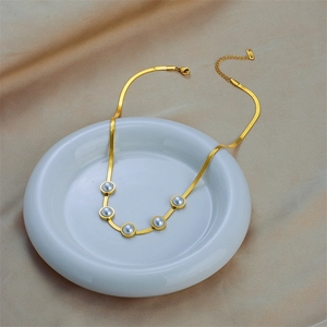 Collana a catena serpente dorata con cinque perle grigie su piatto bianco e seta
