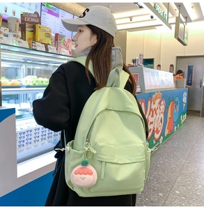 Detail of light green casual backpack with cute pink peach plush charm and side pockets