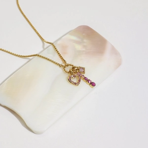 Luxurious gold heart and key necklace with pink zirconia on a decorative shell tray