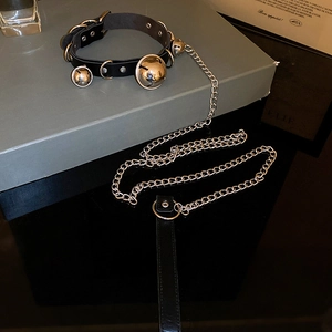 Detailed close-up of a black leather choker featuring three silver bells and a metal chain leash