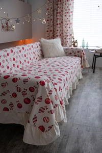 Detailed view of ruffle hem on beige Christmas sofa cover with red festive patterns