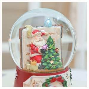 Macro detail of Christmas snow globe with Santa Claus, Xmas tree and red base decoration
