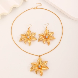 Close-up of gold flower jewelry set with textured petals and clear center gemstones