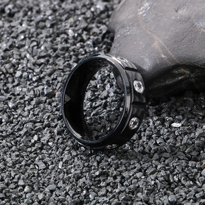 Macro shot of 8mm black titanium ring with inlaid white zircon on dark stone background