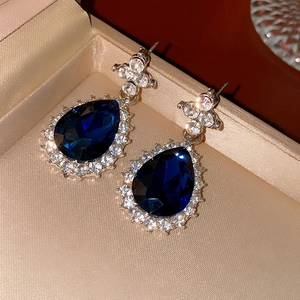Detailed view of silver drop earrings with blue sapphire and diamonds on silk