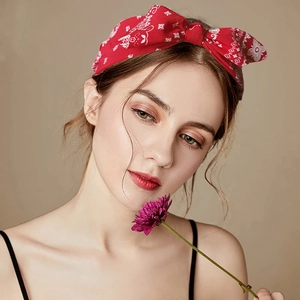 Close-up of a wide red knot headband featuring a white paisley pattern on a model