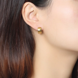 Close-up of a wide gold metal hoop earring with a textured matte finish for women