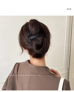 Matte black banana hair clip securing a bun on model from a back-view perspective