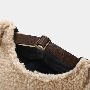 Detail of beige fleece cap with adjustable brown leather strap and bronze metal buckle