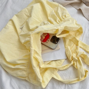Detail view of yellow canvas tote bag showing interior space with phone and books