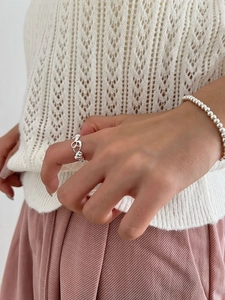 Détail d'une bague multicouche en argent et d'un bracelet à perles sur une main de femme