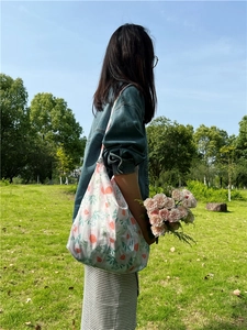 Floral print cotton tote bag shown in outdoor setting with fresh spring landscape