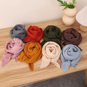 Vue à plat de foulards carrés plissés en coton et lin en 8 couleurs sur table en bois