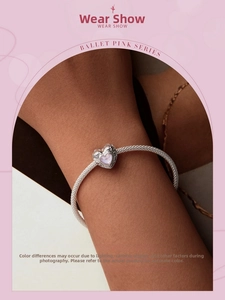 Detail view of s925 silver beaded bracelet with heart pendant and bow charm on wrist