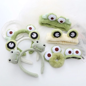 Flat lay of green plush frog hair accessories set including headbands and clips