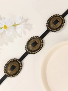 Detail of vintage bronze metal buckles with embossed patterns on black PU leather belt
