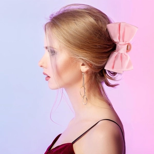 Detail shot of a pink satin bow hair claw clip worn on hair with a silky texture