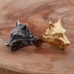 Retro stainless steel wolf head rings in gold and silver finish on a wooden base