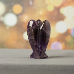 Macro shot of polished 1.5-inch amethyst angel carving with natural crystal textures