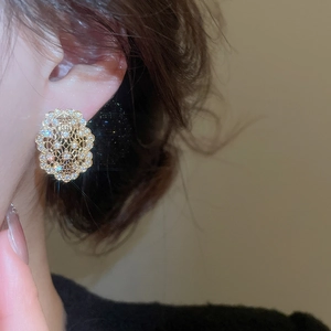 Gros plan de boucles d'oreilles ovales dorées avec zircons sur une oreille féminine