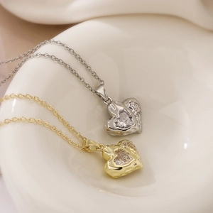 Gold and silver heart-shaped pendant necklaces with zircons on white ceramic