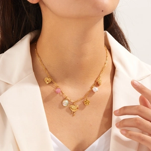 Gold stainless steel necklace with heart flower charms and pearls on a female model